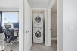 Conveniently located laundry area featuring stacked appliances, with a light switch visible on the wall - 