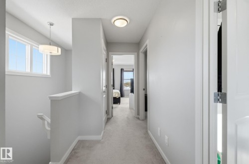 The property features a bright hallway with light-colored carpeting, white walls, and a contemporary ceiling light fixture - 17498 76 St Nw, Edmonton, AB - Indoor Photo Showing Other Room