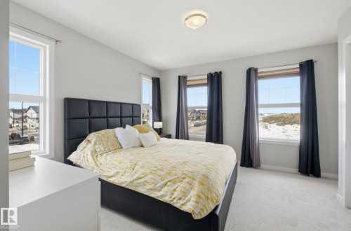 This bedroom offers ample natural light through its windows, complemented by light grey walls and light colored carpet - 17498 76 St Nw, Edmonton, AB - Indoor Photo Showing Bedroom