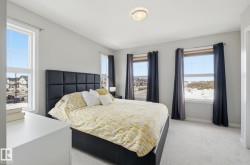 This bedroom offers ample natural light through its windows, complemented by light grey walls and light colored carpet - 