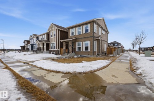 The property features a two-story exterior with light brown siding and white window trim - 17498 76 St Nw, Edmonton, AB - Outdoor With Facade