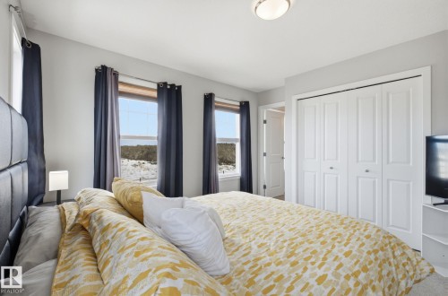 The property features a bedroom with two windows, a ceiling light fixture, and white bi-fold closet doors - 17498 76 St Nw, Edmonton, AB - Indoor Photo Showing Bedroom