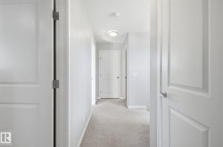 Hallway with light gray walls, white trim, and light gray carpet - 