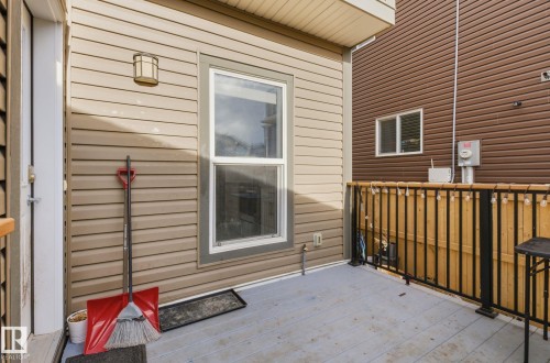 The property features a private outdoor deck with a dark metal railing and a wood privacy fence - 17498 76 St Nw, Edmonton, AB - Outdoor With Exterior