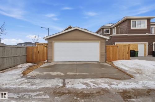 The property includes a detached garage with a white garage door, featuring light brown siding and a brown shingled roof - 17498 76 St Nw, Edmonton, AB - Outdoor