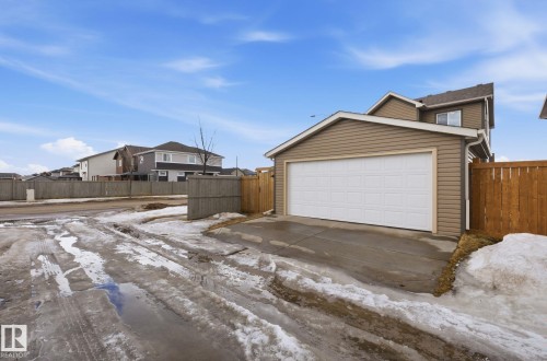 The property features an attached garage with a white sectional door and tan siding - 17498 76 St Nw, Edmonton, AB - Outdoor