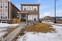 The property features a two-story exterior with brown siding and white window shutters, complemented by a front porch with stone accents and a concrete walkway - 