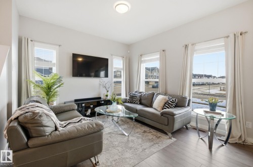 Living area with hardwood flooring, light-colored walls, and large windows with drapes - 17498 76 St Nw, Edmonton, AB - Indoor Photo Showing Living Room