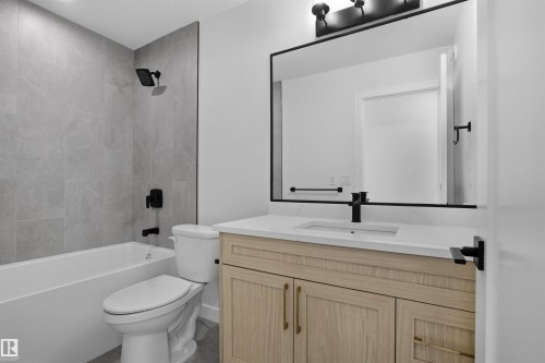 This bathroom features a contemporary vanity with a light wood finish and a white countertop, complemented by a large rectangular mirror with a black frame - 3304 Chickadee Drive, Edmonton, AB - Indoor Photo Showing Bathroom