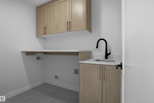 The property features a utility room with light wood cabinetry, a sink with a matte black faucet, and white countertops - 3304 Chickadee Drive, Edmonton, AB - Indoor