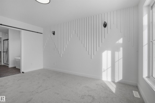 Bright room with light gray carpeting, featuring a decorative accent wall with vertical panels, and natural light from a window - 3304 Chickadee Drive, Edmonton, AB - Indoor Photo Showing Other Room