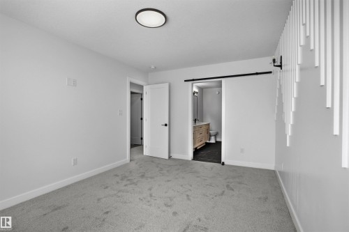 This room features a modern ceiling light fixture, light gray carpet, and white walls with white baseboards - 3304 Chickadee Drive, Edmonton, AB - Indoor Photo Showing Other Room