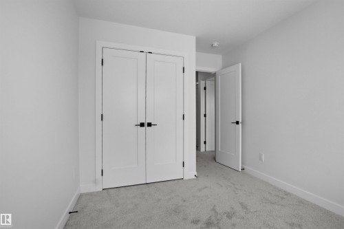 This room features light grey carpeting, white walls, and white doors with matte black hardware - 3304 Chickadee Drive, Edmonton, AB - Indoor Photo Showing Other Room