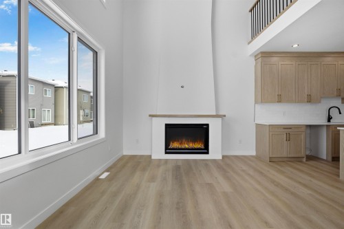 The property features an open-concept living area with light-colored flooring and white walls - 3304 Chickadee Drive, Edmonton, AB - Indoor Photo Showing Living Room With Fireplace
