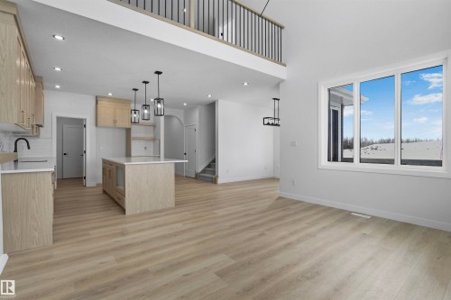 Open concept living space featuring light wood flooring, white walls, and a kitchen with light wood cabinetry and a central island - 3304 Chickadee Drive, Edmonton, AB - Indoor Photo Showing Kitchen
