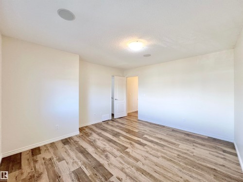 This spacious room features light-colored walls and wood-style flooring, creating a bright and inviting atmosphere - 17127 7A Avenue, Edmonton, AB - Indoor Photo Showing Other Room