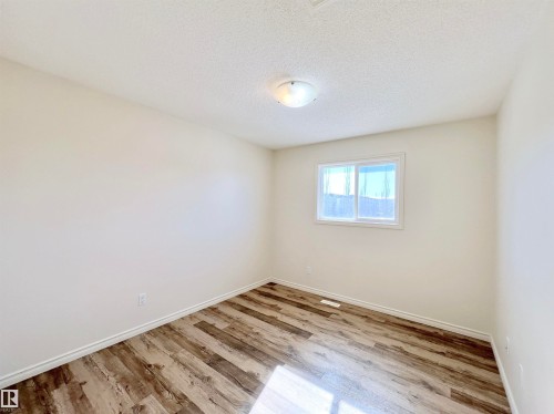 This room features durable plank flooring, a window for natural light, and a ceiling light fixture - 17127 7A Avenue, Edmonton, AB - Indoor Photo Showing Other Room