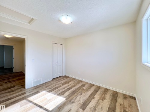 This room features wood-look flooring, a closet with bi-fold doors, and a window providing natural light - 17127 7A Avenue, Edmonton, AB - Indoor Photo Showing Other Room