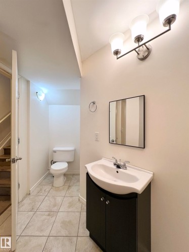 Bathroom featuring a vanity with a dark cabinet, a white sink, and a wall-mounted mirror - 17127 7A Avenue, Edmonton, AB - Indoor Photo Showing Bathroom