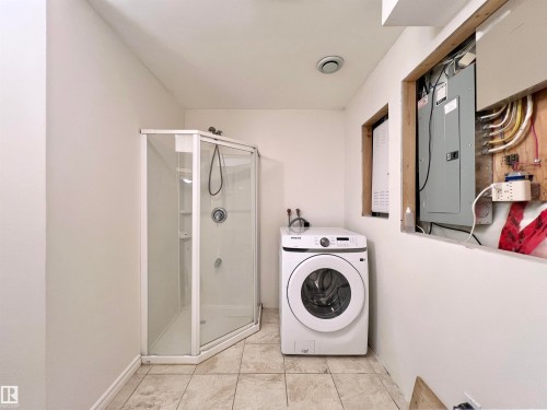 Utility space featuring a corner shower enclosure, a front-loading washing machine, and tiled flooring - 17127 7A Avenue, Edmonton, AB - Indoor Photo Showing Laundry Room