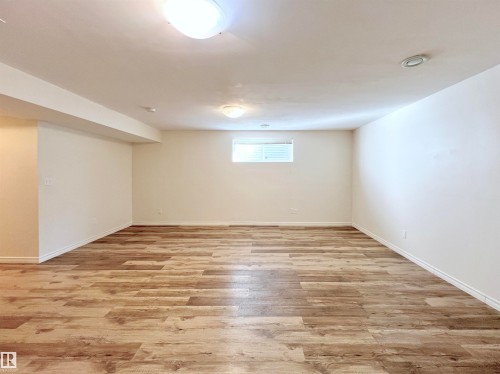 Spacious room featuring wood-look flooring, neutral-toned walls, and recessed lighting - 17127 7A Avenue, Edmonton, AB - Indoor Photo Showing Basement