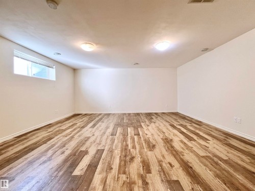 This spacious room features light-toned walls, wood-look flooring, and recessed lighting, offering a versatile space - 17127 7A Avenue, Edmonton, AB - Indoor Photo Showing Other Room