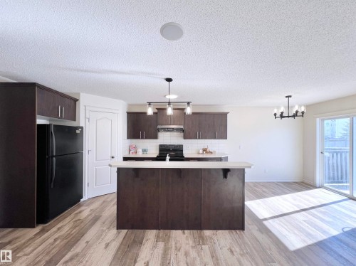 The property features an open-concept kitchen and living area with wood-look flooring - 17127 7A Avenue, Edmonton, AB - Indoor Photo Showing Kitchen