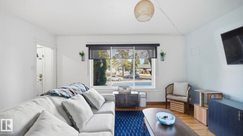 The property features a bright living area with light-colored walls and large windows, offering views of the street - 10922 117 Street, Edmonton, AB - Indoor Photo Showing Living Room