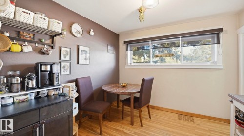 The property features hardwood floors, a built-in cabinet with a black countertop, and a window with views of trees - 10922 117 Street, Edmonton, AB - Indoor Photo Showing Dining Room