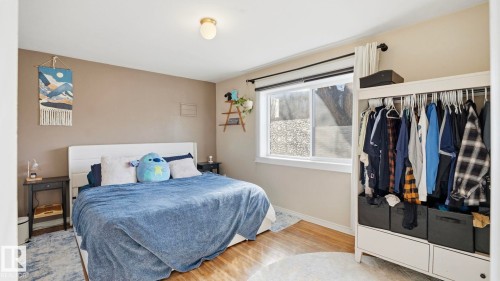 This room features light-colored walls, hardwood flooring, and a window providing natural light - 10922 117 Street, Edmonton, AB - Indoor Photo Showing Bedroom