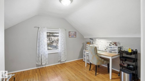 This space features hardwood floors, a window with curtains, and sloped ceilings - 10922 117 Street, Edmonton, AB - Indoor