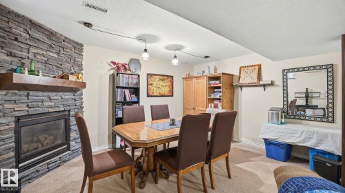 The living area features a stone-clad fireplace with a wood mantle, carpeted flooring, and recessed lighting - 10922 117 Street, Edmonton, AB - Indoor With Fireplace