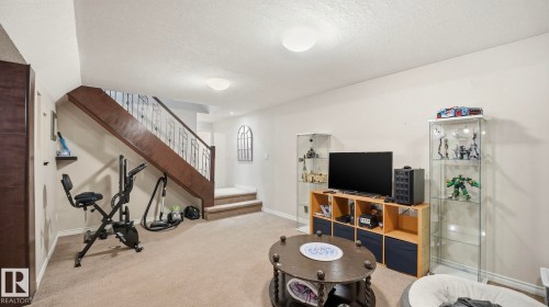 The property features a staircase with a dark wood handrail and decorative metal balusters, leading to an upper level - 10922 117 Street, Edmonton, AB - Indoor Photo Showing Other Room