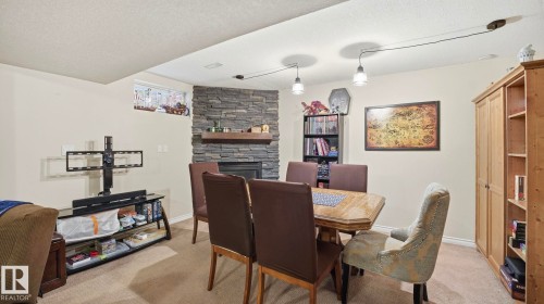 The property features a spacious room with light-colored walls and carpeted flooring - 10922 117 Street, Edmonton, AB - Indoor Photo Showing Dining Room With Fireplace