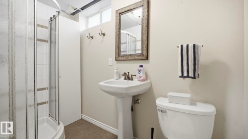 The bathroom features a glass-enclosed shower, a pedestal sink with a mirror, and a toilet - 10922 117 Street, Edmonton, AB - Indoor Photo Showing Bathroom