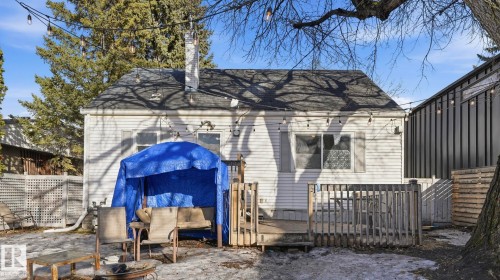 The property features a rear exterior with white siding, a dark shingled roof, and a visible chimney - 10922 117 Street, Edmonton, AB - Outdoor