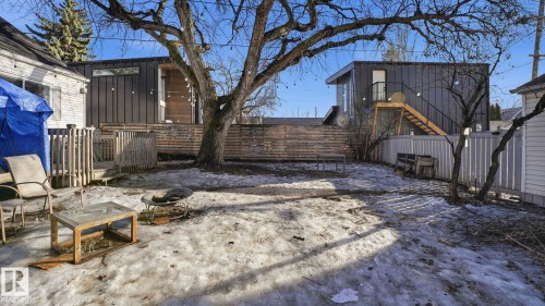The property features a spacious backyard with a large tree and a wooden privacy fence - 10922 117 Street, Edmonton, AB - Outdoor
