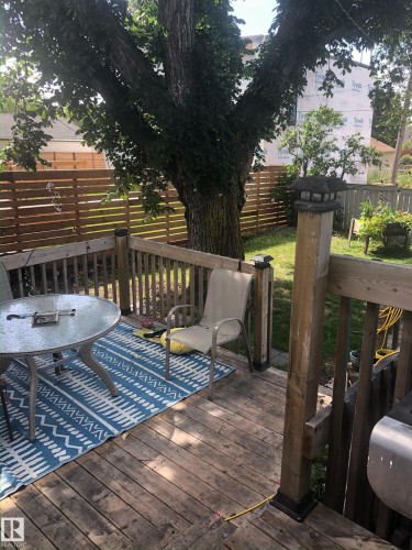 The property features a wooden deck with a railing and a large, mature tree providing shade - 10922 117 Street, Edmonton, AB - Outdoor With Deck Patio Veranda