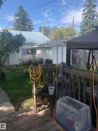 The property features a wood deck with a railing, overlooking a green lawn - 10922 117 Street, Edmonton, AB - Outdoor With Deck Patio Veranda