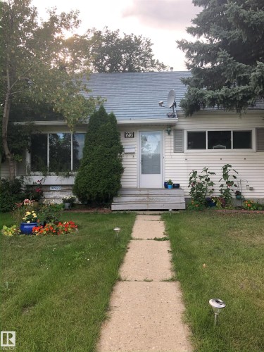 The property features white siding, a light blue roof, and a front yard with a concrete pathway and green grass - 10922 117 Street, Edmonton, AB - Outdoor