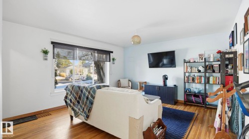 This inviting living area features hardwood floors and a large window, providing natural light and a view of the street - 10922 117 Street, Edmonton, AB - Indoor