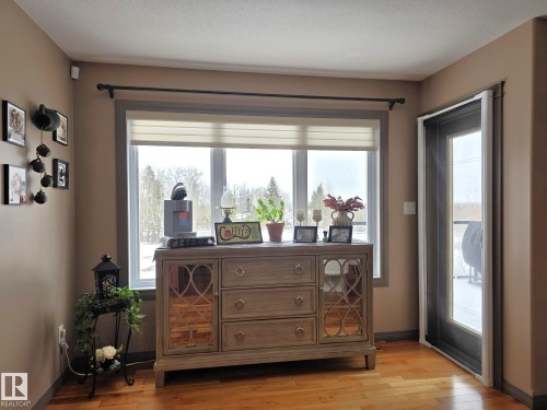 The property features hardwood floors and a large window with a view of mature trees - 4477 36 Street, Drayton Valley, AB - Indoor Photo Showing Other Room