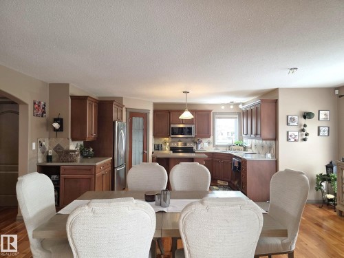 The main level features hardwood flooring, a dining area, and a kitchen with wood cabinetry, stainless steel appliances, and a window - 4477 36 Street, Drayton Valley, AB - Indoor Photo Showing Dining Room