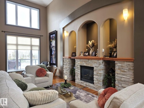Living area featuring a stone-clad fireplace with a wood mantelpiece, built-in wall niches, and large windows - 4477 36 Street, Drayton Valley, AB - Indoor Photo Showing Living Room With Fireplace