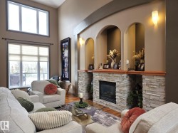 Living area featuring a stone-clad fireplace with a wood mantelpiece, built-in wall niches, and large windows - 