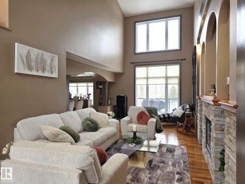 The living area features high ceilings, hardwood flooring, and large windows that provide natural light - 4477 36 Street, Drayton Valley, AB - Indoor Photo Showing Living Room With Fireplace