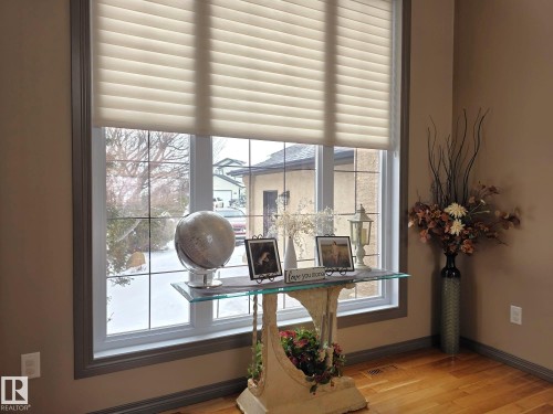 The interior features hardwood flooring and a large window with privacy blinds, framed by neutral-toned walls - 4477 36 Street, Drayton Valley, AB - Indoor Photo Showing Other Room