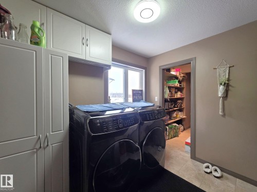 The property features a dedicated laundry area with overhead cabinetry, a window providing natural light, and a tiled floor - 4477 36 Street, Drayton Valley, AB - Indoor Photo Showing Laundry Room