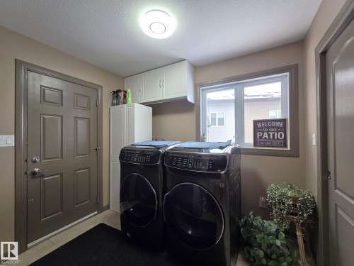 Laundry area featuring overhead cabinetry, a window, and a door - 4477 36 Street, Drayton Valley, AB - Indoor Photo Showing Laundry Room