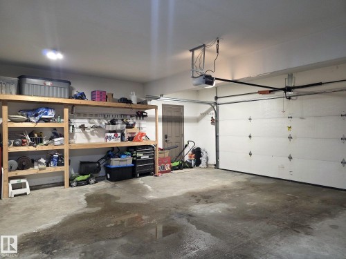 This garage features a concrete floor, built-in shelving, an overhead garage door, and an automatic garage door opener - 4477 36 Street, Drayton Valley, AB - Indoor Photo Showing Garage